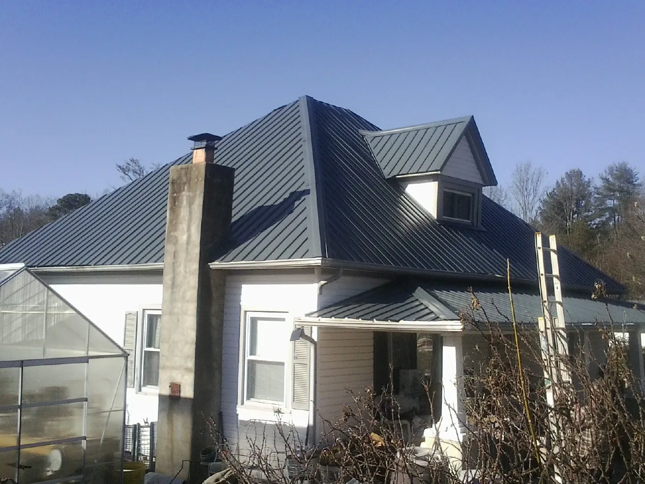 Dark blue standing seam metal roof on a white farmhouse with dormer — Slate & Tile Roof Repair by Roofing Brothers in Rocky Face