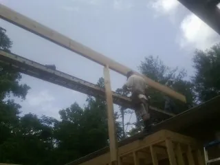 Carpenter setting a ridge beam over a new addition frame — Ice Dam Removal by Roofing Brothers in Rocky Face