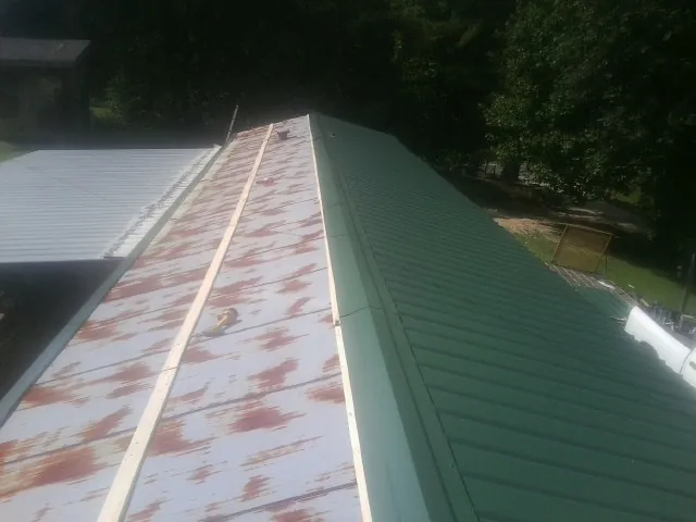 Old rusted panels beside newly installed green metal roofing — Wind Damage Roof Repair by Roofing Brothers in Rocky Face