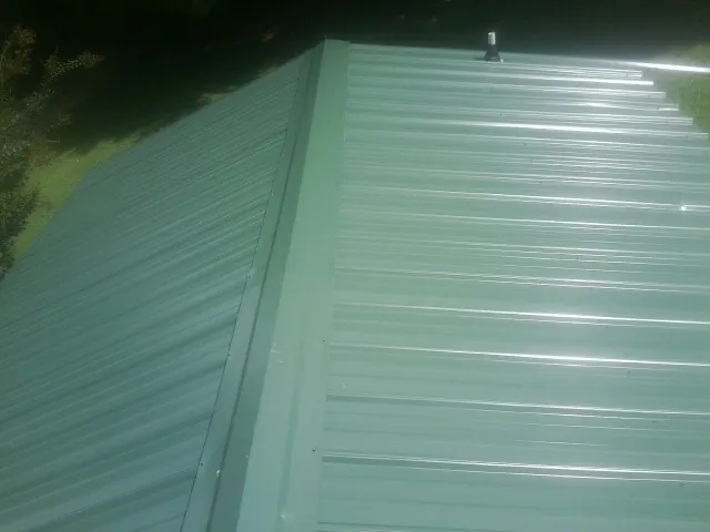 New green metal panels meeting at the ridge of a roof — Flat Roof Repair work by our crew in Rocky Face