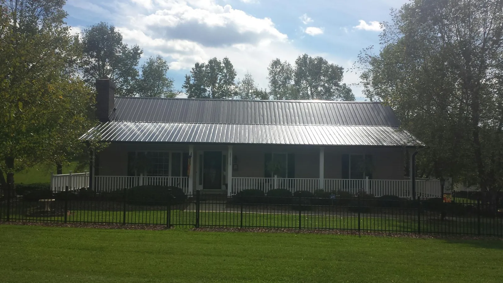 Gray metal roof on a brick ranch with a full width front porch — Gutter Guard Installation work by our crew in Rocky Face
