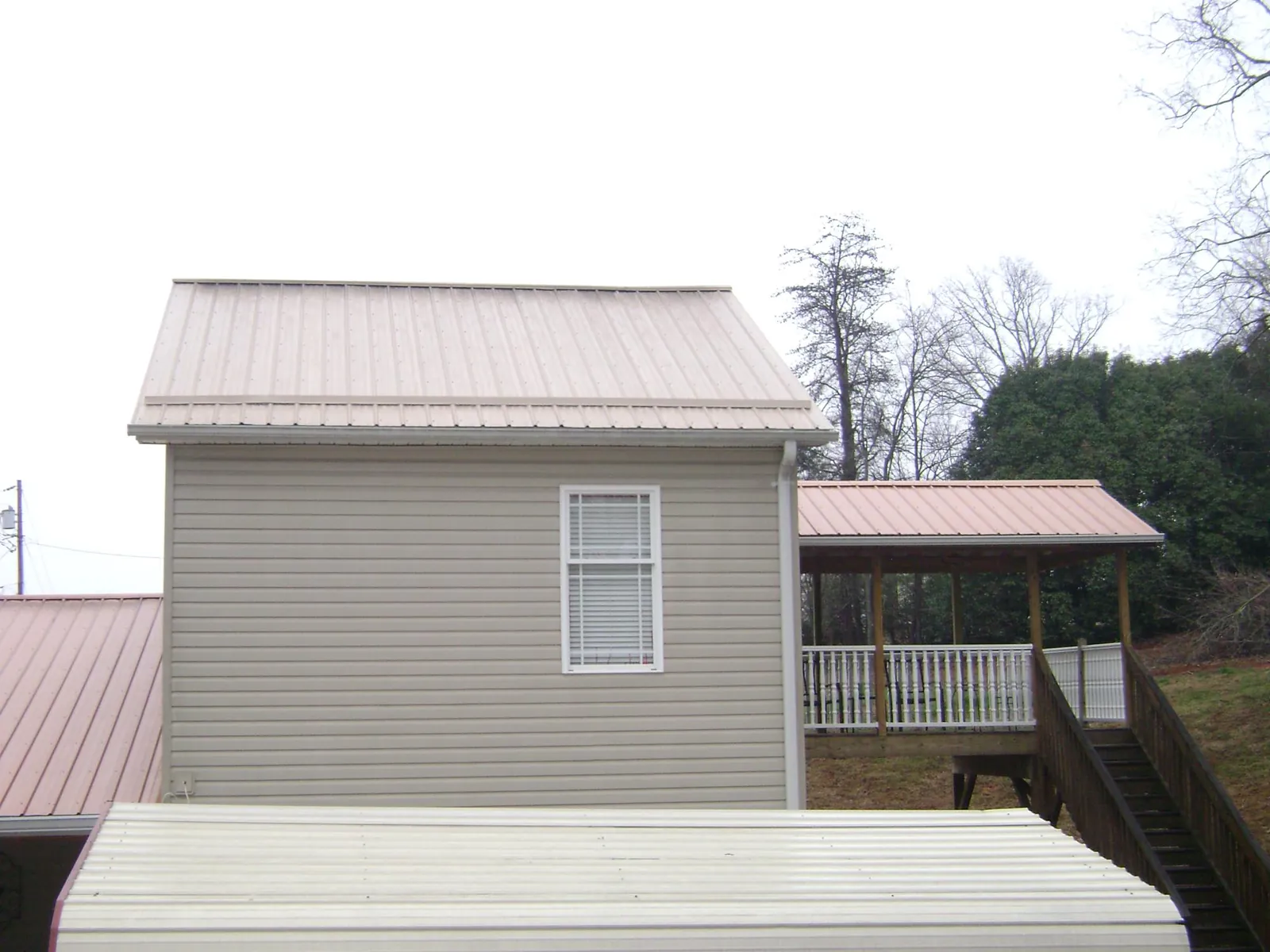 Tan metal roofs on a two story addition and attached porch, from a Roof Replacement job in Rocky Face