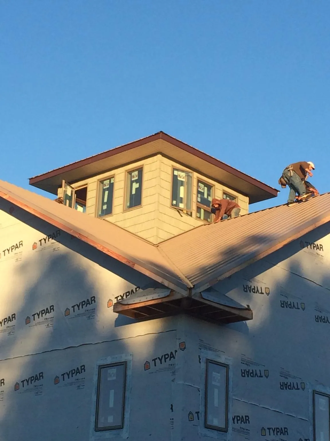 Roofers working around a rooftop cupola on a new metal roof at sunset — Roof Waterproofing in Rocky Face by Roofing Brothers